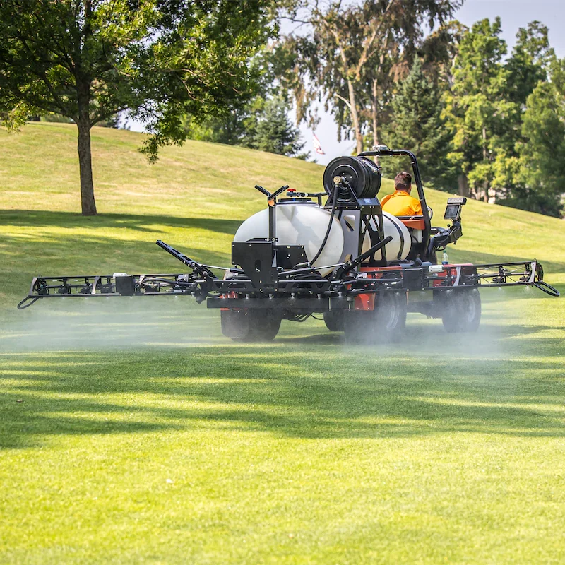 Smithco Spray Star 1200 E turf maintenance sprayer in action, equipped with a large tank and spray boom, demonstrating eco-friendly application on a golf course.